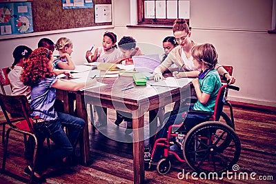 Pretty teacher helping pupils in classroom Stock Photo