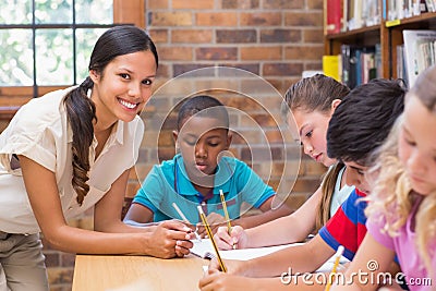 Pretty teacher helping pupils in library Stock Photo