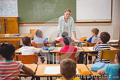 Pretty teacher talking to the young pupils in classroom Stock Photo