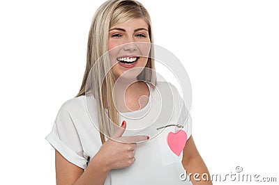 Pretty teen pointing towards pink paper heart Stock Photo