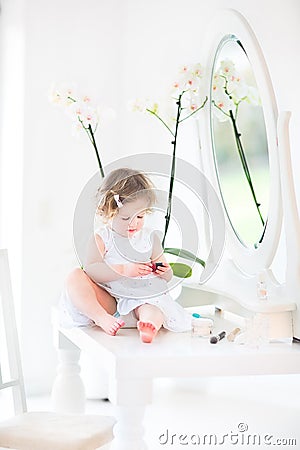 Pretty toddler girl with curly hair playing with make up Stock Photo