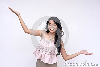 A pretty and vivacious young asian woman with hands stretched, presenting a topic or something with eagerness. on a white Stock Photo