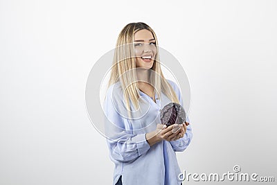 Pretty woman in blue outfit holding single cabbage on white background Stock Photo