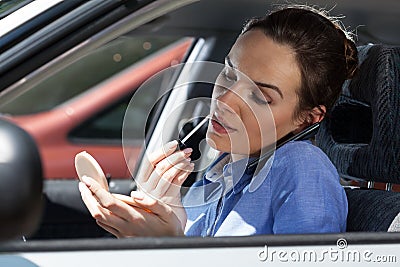 Pretty woman in a car doing makeup while standing in a traffic jam Stock Photo