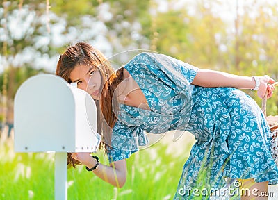 Pretty woman is checking her white mail box in a country farm house field Stock Photo