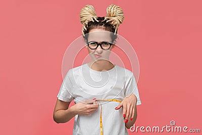 Girl with dreads in a white shirt and glasses looking is upset measuring her boobs Stock Photo