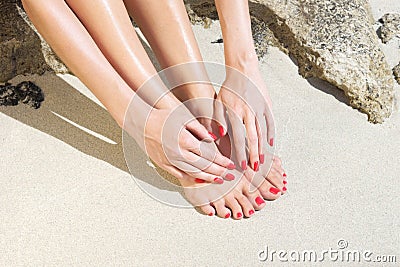 Pretty woman feet with red manicure and pedicure: relaxing on sand. Stock Photo