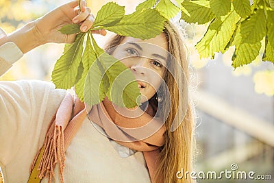 Pretty woman with green chestnut leaves in park outdoors Stock Photo