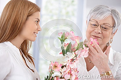 Pretty woman greeting mother with flowers smiling Stock Photo