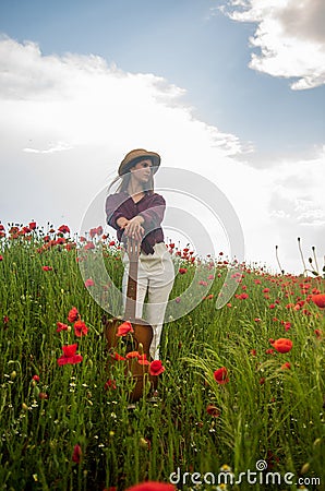 pretty woman in hat walking in poppy field. girl in meadow. romantic mood. beauty of spring nature. happy girl with Stock Photo