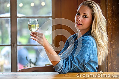 Pretty woman holding up a pint of craft cider or beer in a tulip glass at local brewery Stock Photo