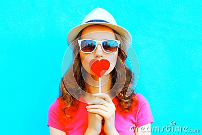 Pretty woman kissing red lollipop shape of a heart Stock Photo