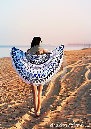 Pretty woman with a mandala round beach tapestry in the ocean co Stock Photo