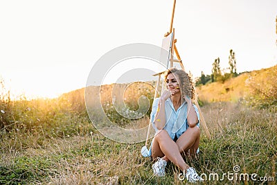 Pretty woman is painting. Open air session. Cute woman draws a picture at sunset. girl artist. Stock Photo