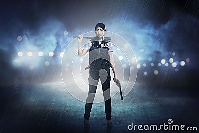 Pretty woman in police vest holding baseball bat Stock Photo