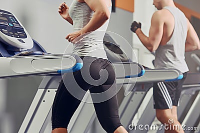 Pretty woman running on treadmill with fit young man on background Editorial Stock Photo