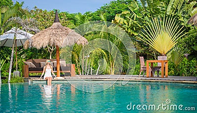 A Pretty woman sitting in the tropical shade a pool 3 Stock Photo