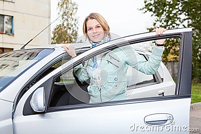 Pretty woman standing behind car with opened door Stock Photo