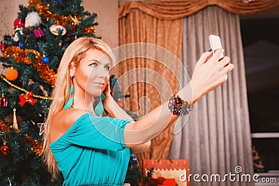 Pretty woman taking selfie photo on mobile phone Christmas tree Stock Photo