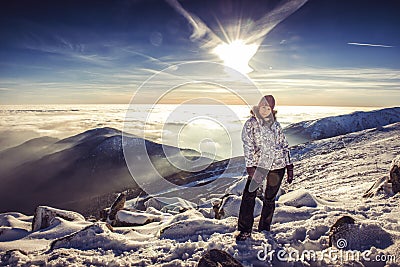 Pretty woman on top of mountain, female hiker admiring winter scenery on a mountaintop alone Stock Photo