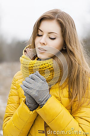 Pretty woman in a yellow knit scarf. Warm hands. Looking down. Stock Photo