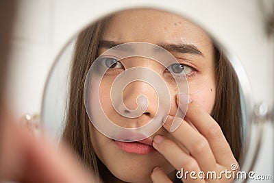 Pretty women are looking at the mirror to see the facial wrinkles. Stock Photo