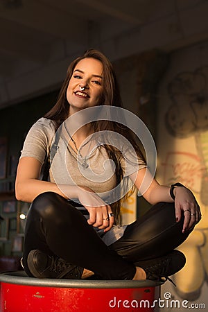 Pretty yong woman with piercing and long hair on red barrel Stock Photo