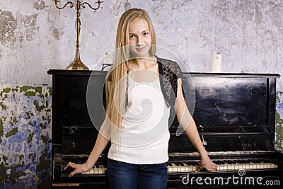 pretty young blond real girl at piano in old-style rusted interior, vintage concept Stock Photo