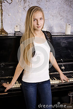 pretty young blond real girl at piano in old-style rusted interior, vintage concept Stock Photo