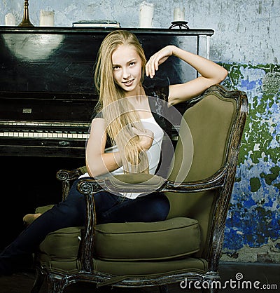 Pretty young blond real girl at piano in old-style rusted interior, vintage concept Stock Photo