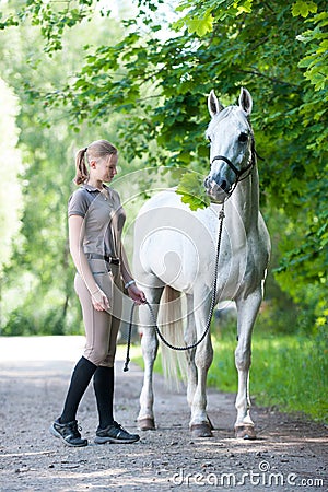 Pretty young blondy teenage girl with her favorite white horse. Stock Photo