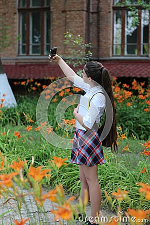 Girl- schoolgirl with long hair in school uniform makes selfie Stock Photo