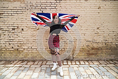 Pretty young girl in punk style with the london flag on her shoulders celebrating some national event. Patriotic concept Stock Photo