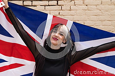 Pretty young girl in punk style with the london flag on her shoulders celebrating some national event. Patriotic concept Stock Photo