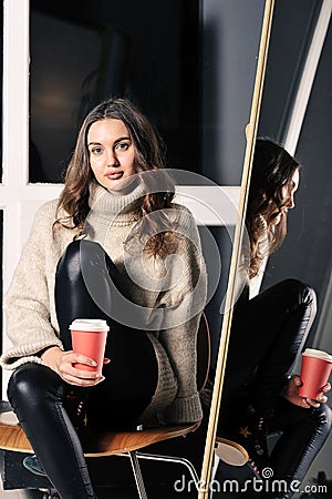 pretty young girl is sitting on a chair in leather trousers Stock Photo