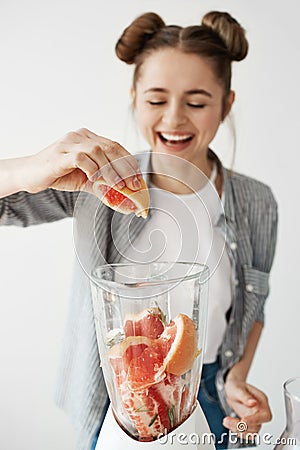 Pretty young girl smiling blending detox refreshing grapefruit smoothie over white wall. Healthy food concept. Stock Photo