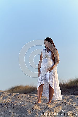 Pretty young pregnant woman with bare feet on the sand Stock Photo