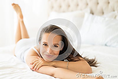 Pretty young woman on bed in modern apartment smiling after wake up. Stock Photo