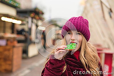 Pretty young woman eating delicious christmas gingerbread at the Stock Photo