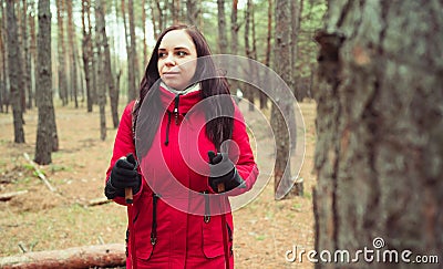 A pretty young woman is engaged in the nordic walking in woods. Stock Photo