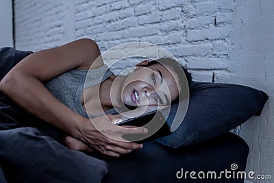pretty young woman on her smart phone late at night falling asleep on the internet. Stock Photo