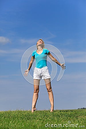 Pretty young woman jumping on green grass against Stock Photo