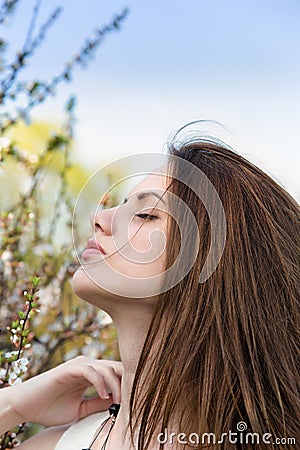 Pretty young woman near tree with flowers Stock Photo