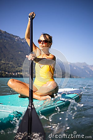 Pretty, young woman paddling on a paddle board on a lake Stock Photo