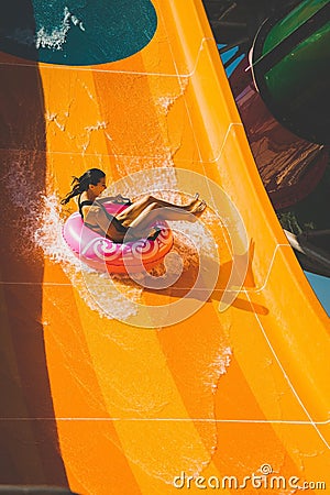 Girl having fun on the orange water slide in aqua park Stock Photo