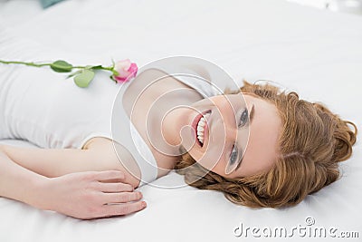 Pretty young woman resting in bed with a rose Stock Photo