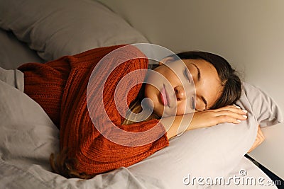 Pretty young woman sleeps hugging pillow on bed at night Stock Photo