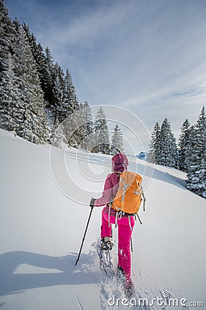 Pretty, young woman snowshoeing in high mountains Stock Photo