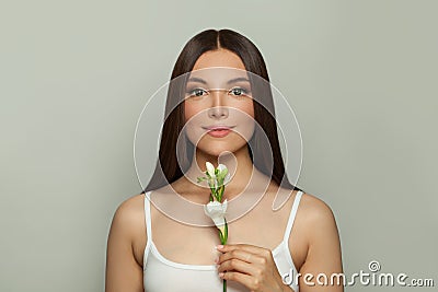 Pretty young woman spa model with clear skin smiling holding flower. Skincare, wellness and facial treatment concept Stock Photo