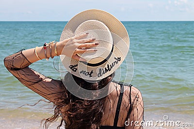 Pretty young woman in summer vacation wearing straw hat enjoying the view at the ocean Stock Photo